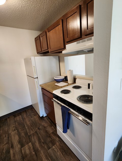 A kitchen with a white refrigerator, white stove, and brown cabinets.