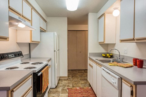 A kitchen with white appliances and wooden cabinets.
