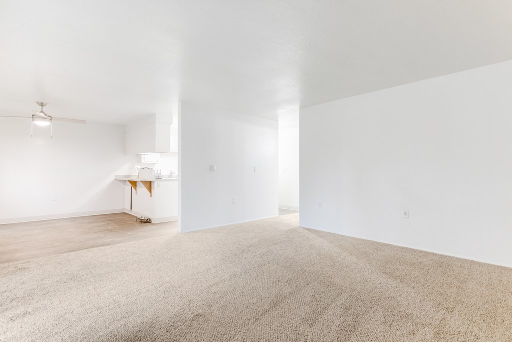 an empty living room with white walls and carpet