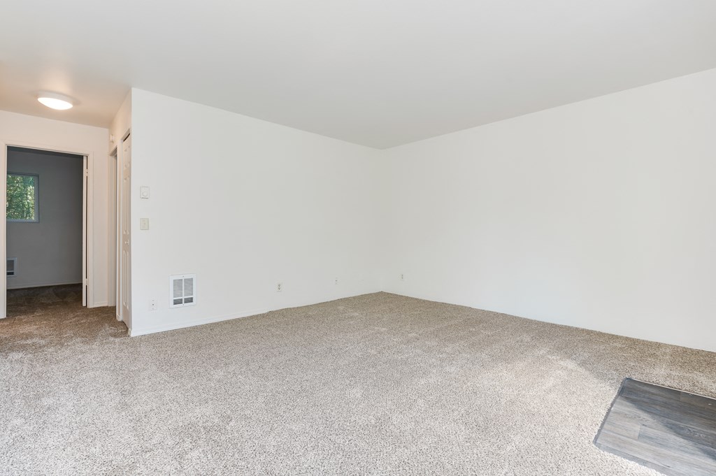an empty living room with white walls and a carpeted floor