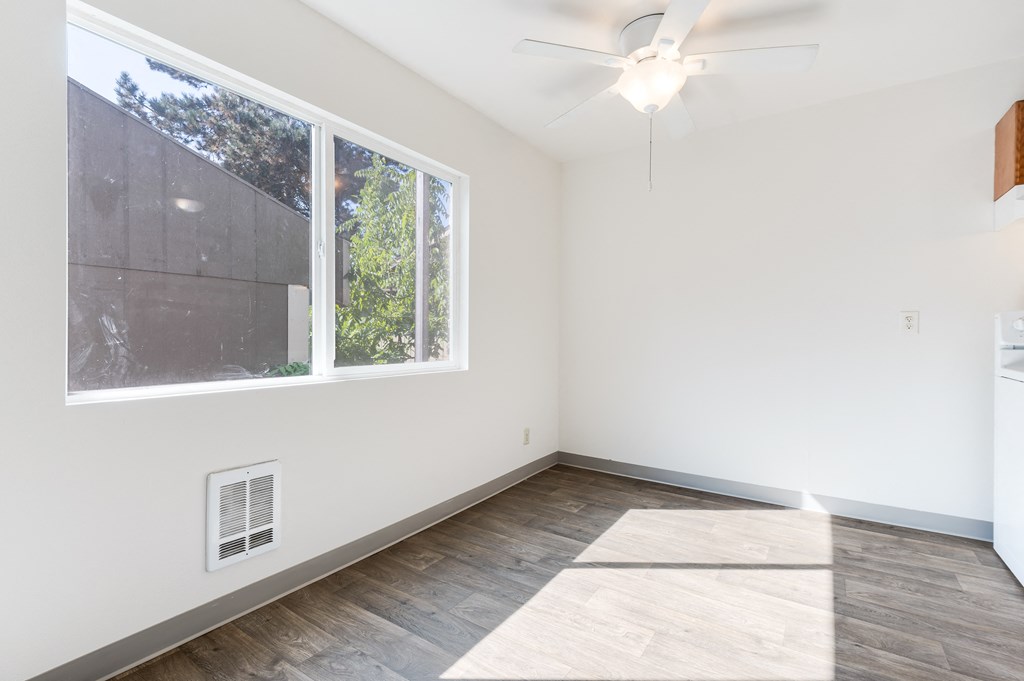 an empty room with a large window and a ceiling fan