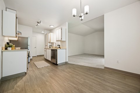 A kitchen with white cabinets and a wooden floor.
