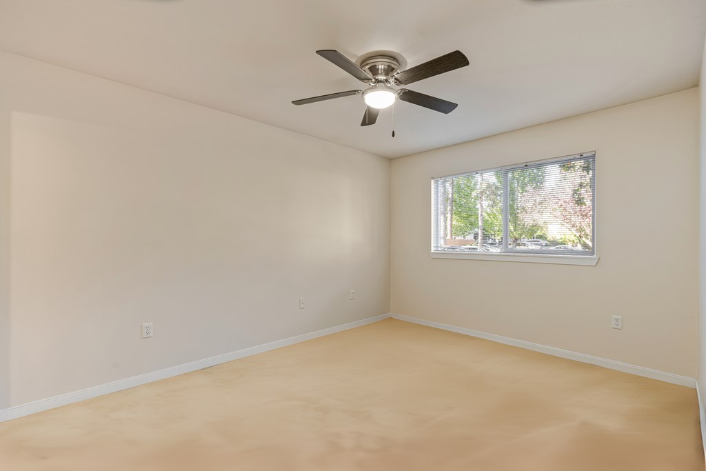 Empty room with a ceiling fan and a window.