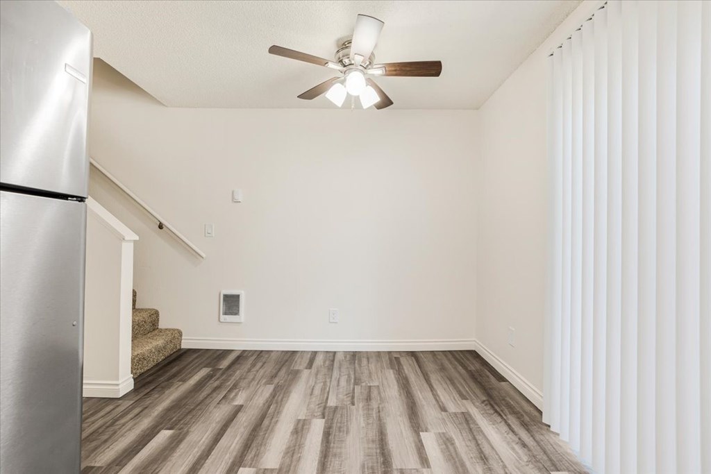 A room with a ceiling fan and wooden flooring.