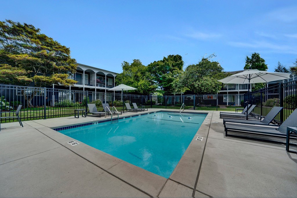 a swimming pool with lounge chairs and umbrellas in front of a building Sunset Station Apartments Portland Oregon 