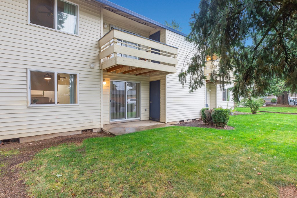 the front of a white house with a porch and a green lawn