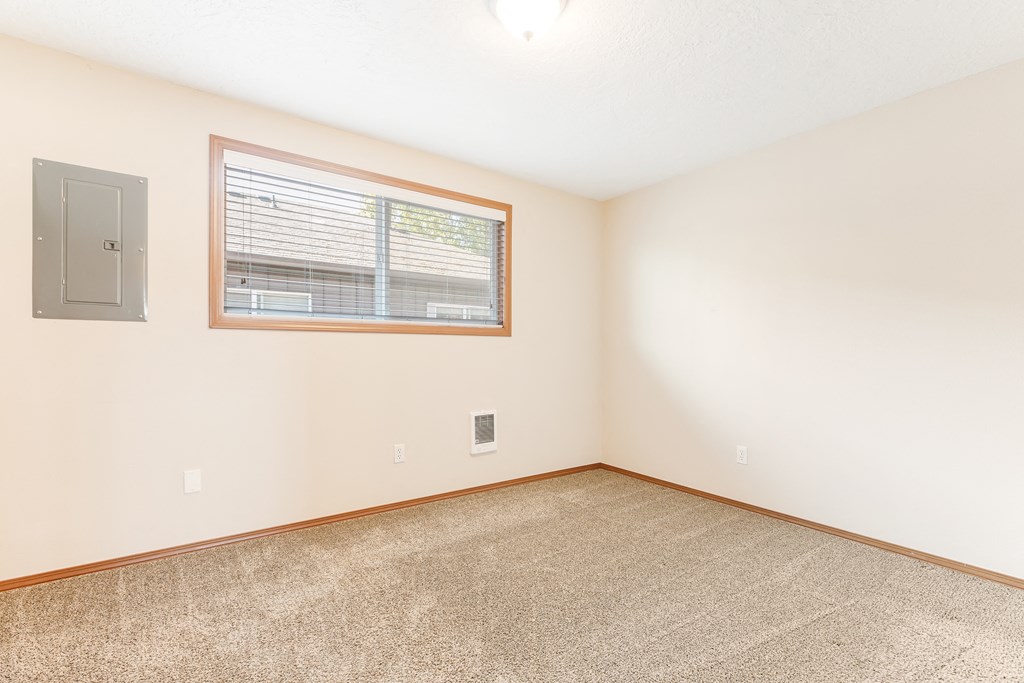 a bedroom with white walls and a large window