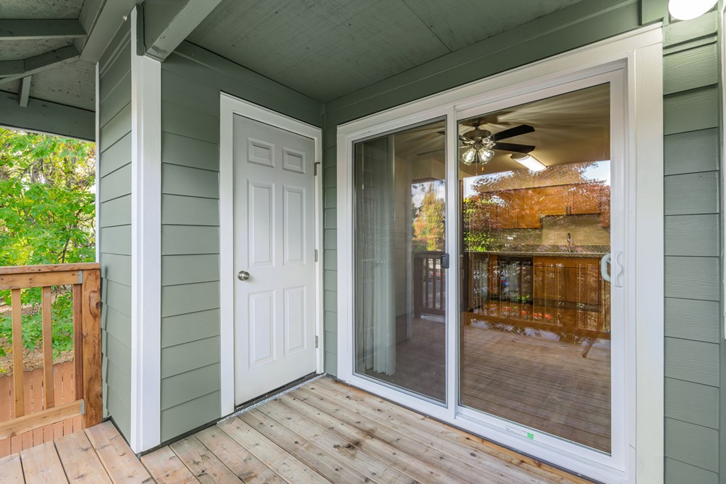A white door and sliding glass window on a porch.