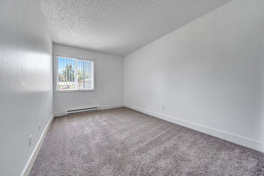 a bedroom with a large window and a carpeted floor