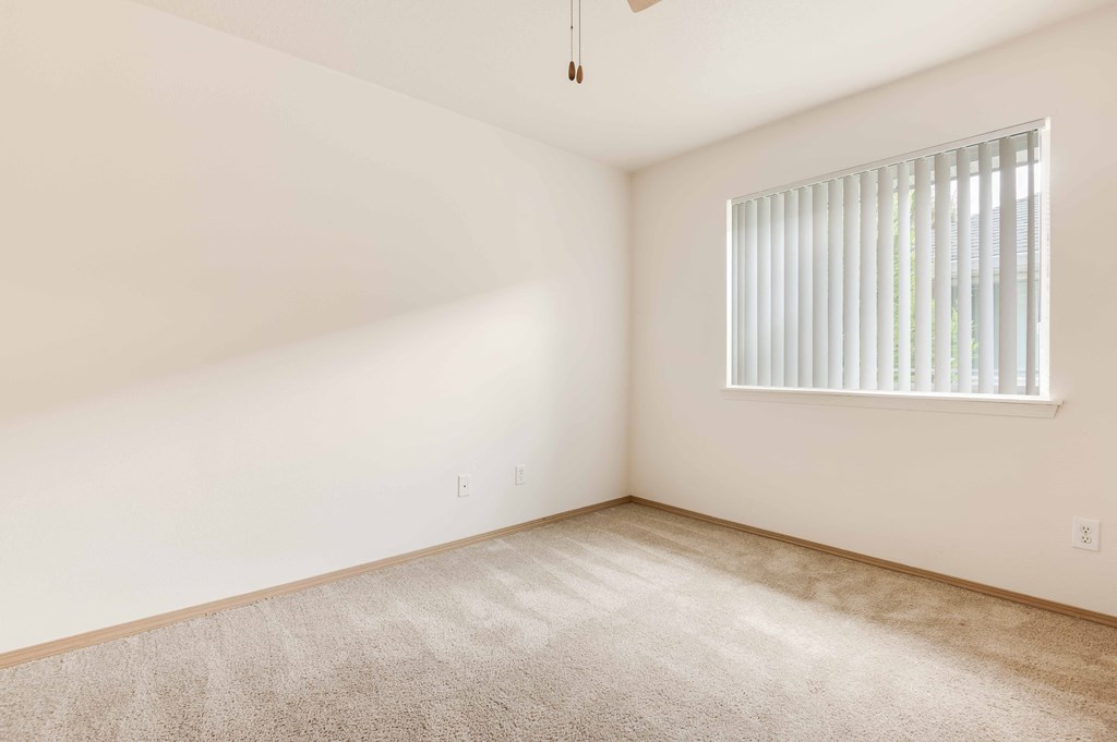 a bedroom with white walls and a window