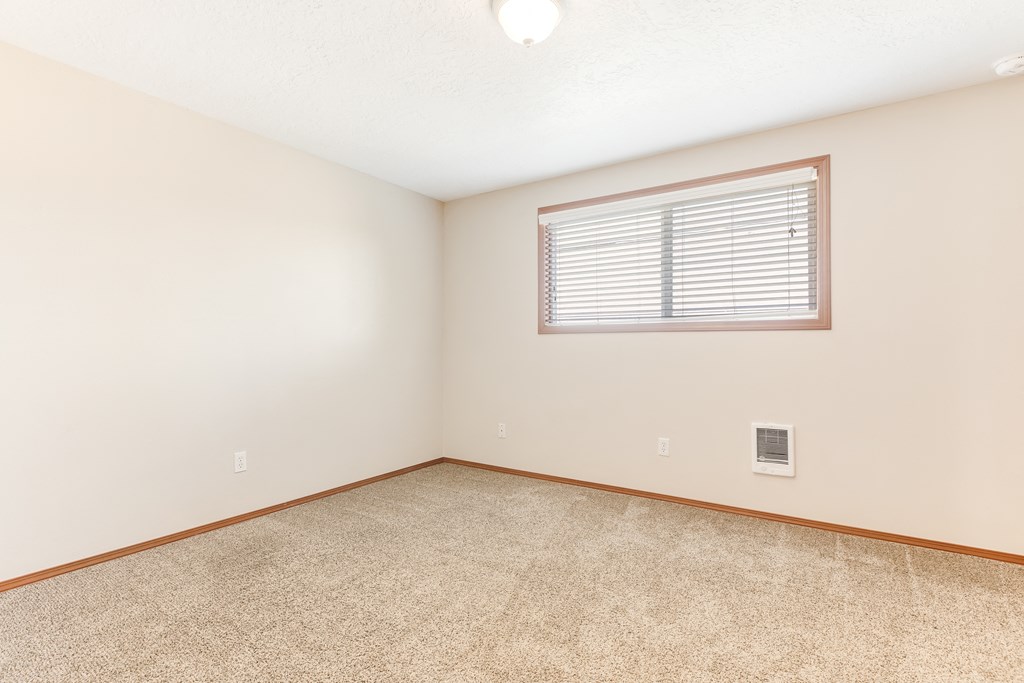 a bedroom with white walls and a window