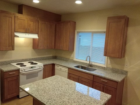 A kitchen with granite countertops and wooden cabinets.