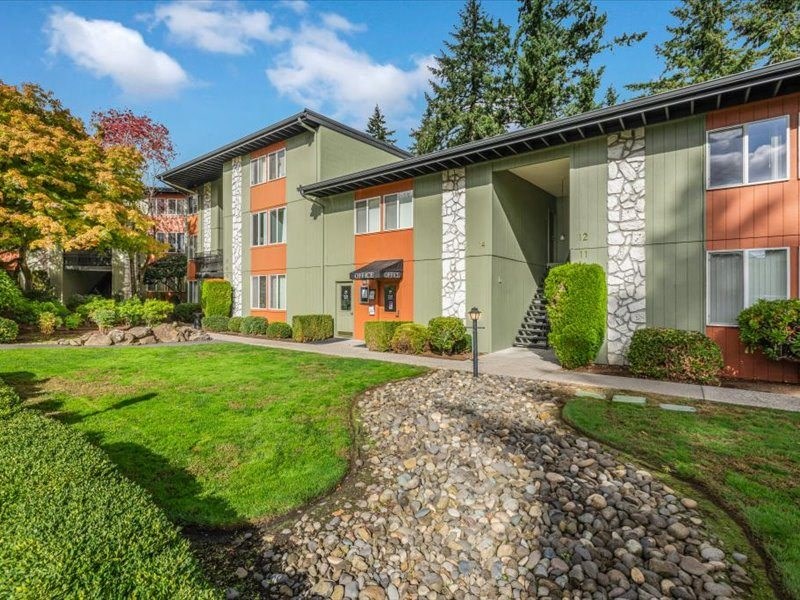 a green and orange apartment building with a walkway and grass