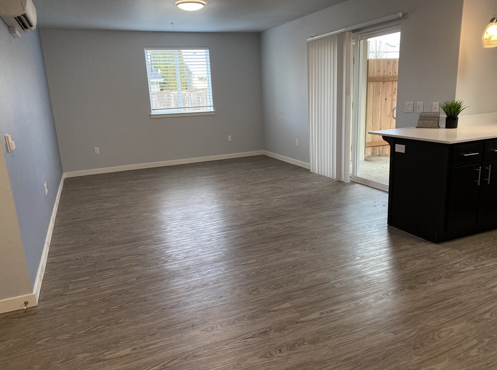 A room with a wooden floor and a window with blinds.