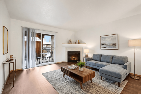 A living room with a grey couch, a coffee table, a fireplace, and a painting on the wall.