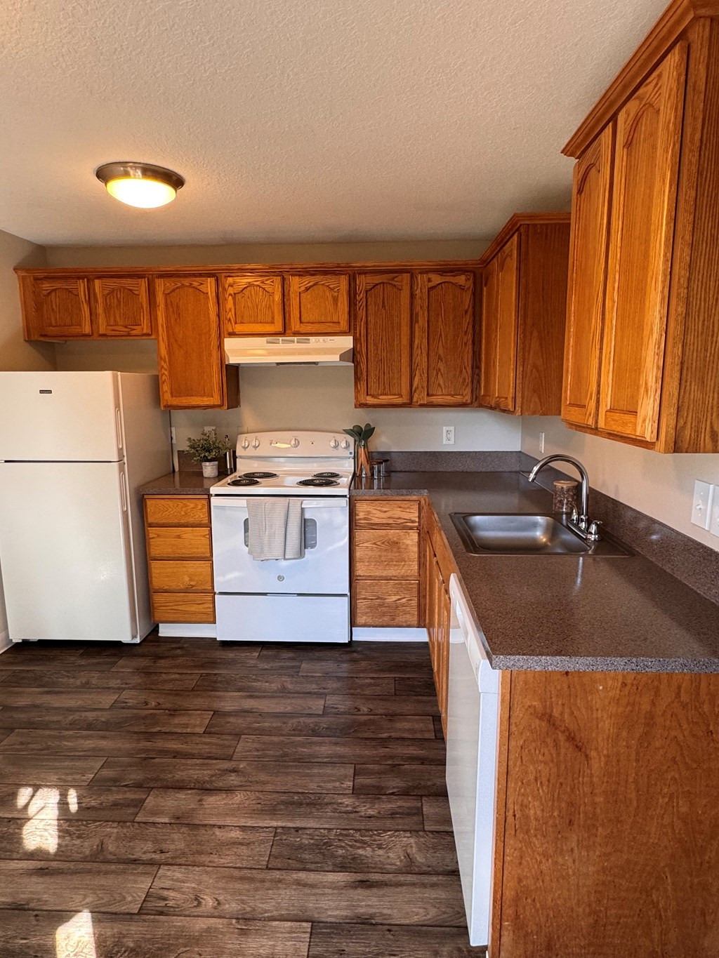 A kitchen with wooden cabinets and a white stove top oven.