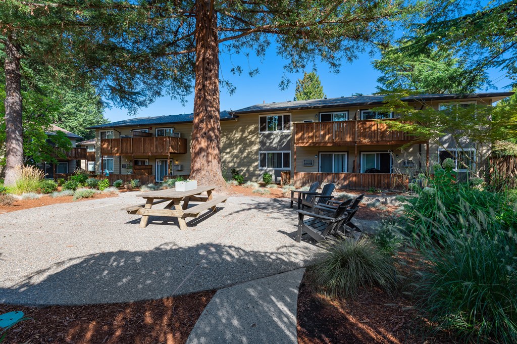 a picnic area with benches and trees in front of a building