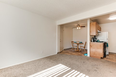A kitchen area with a table and chairs is visible through an open doorway.