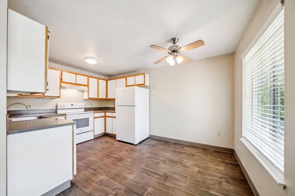 A kitchen with white cabinets and a wooden floor.