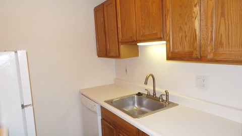 A kitchen with a white counter top and wooden cabinets.