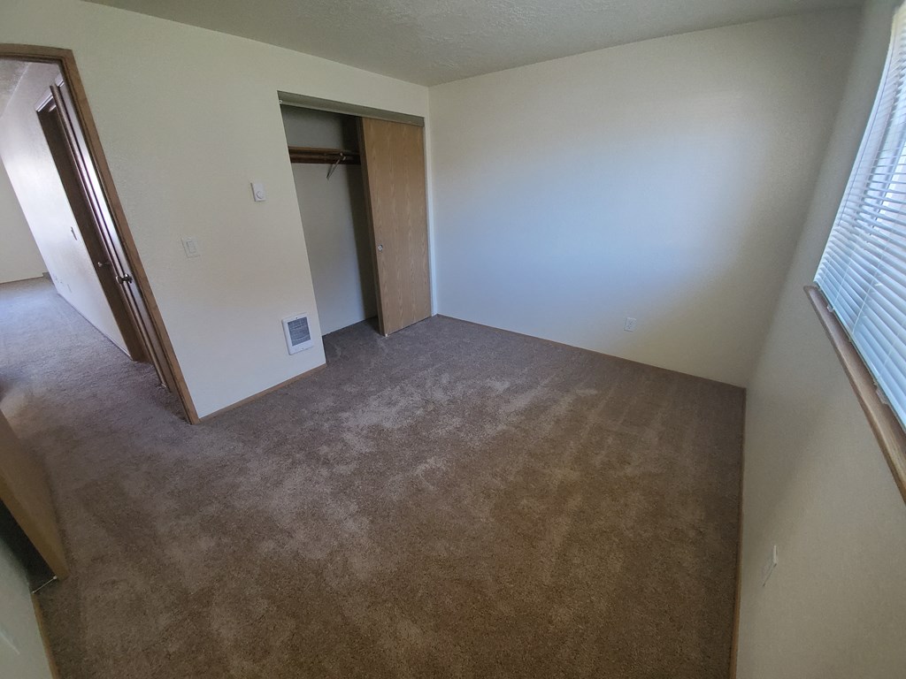 an empty bedroom with a closet and a window