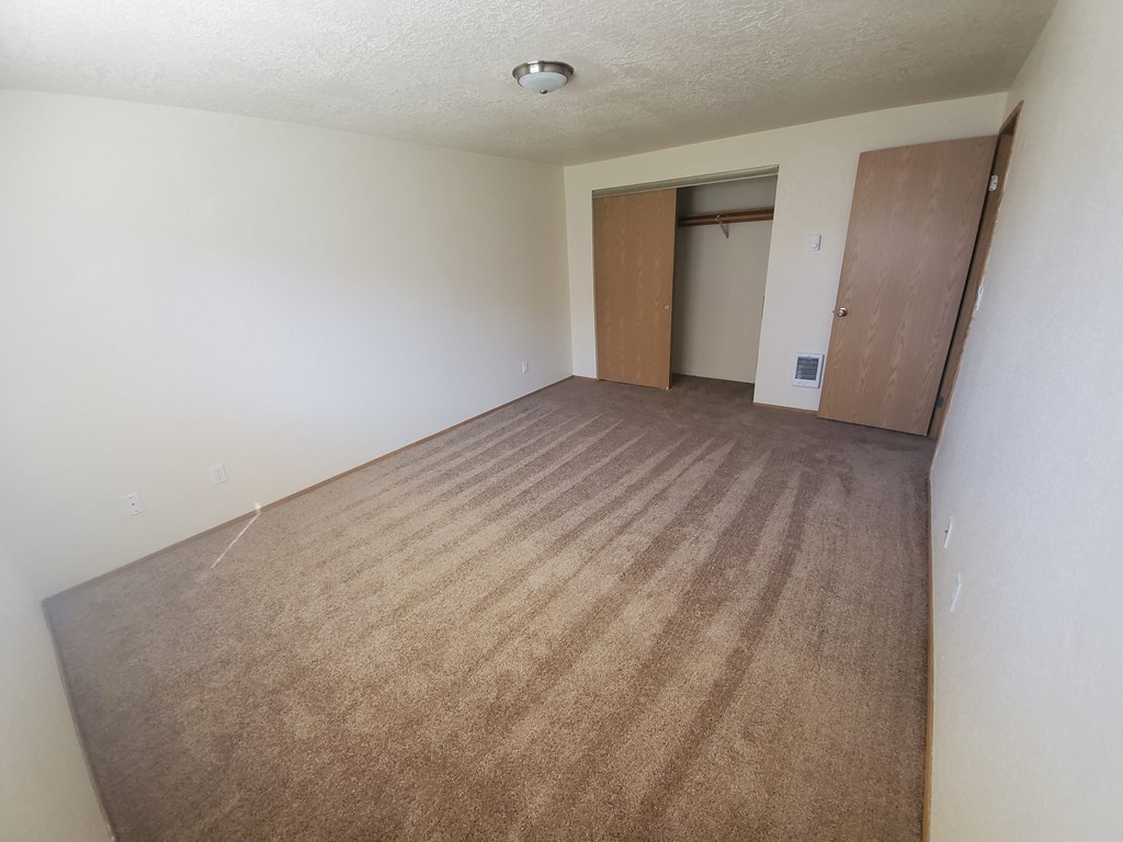 an empty room with a carpeted floor and a door in the background