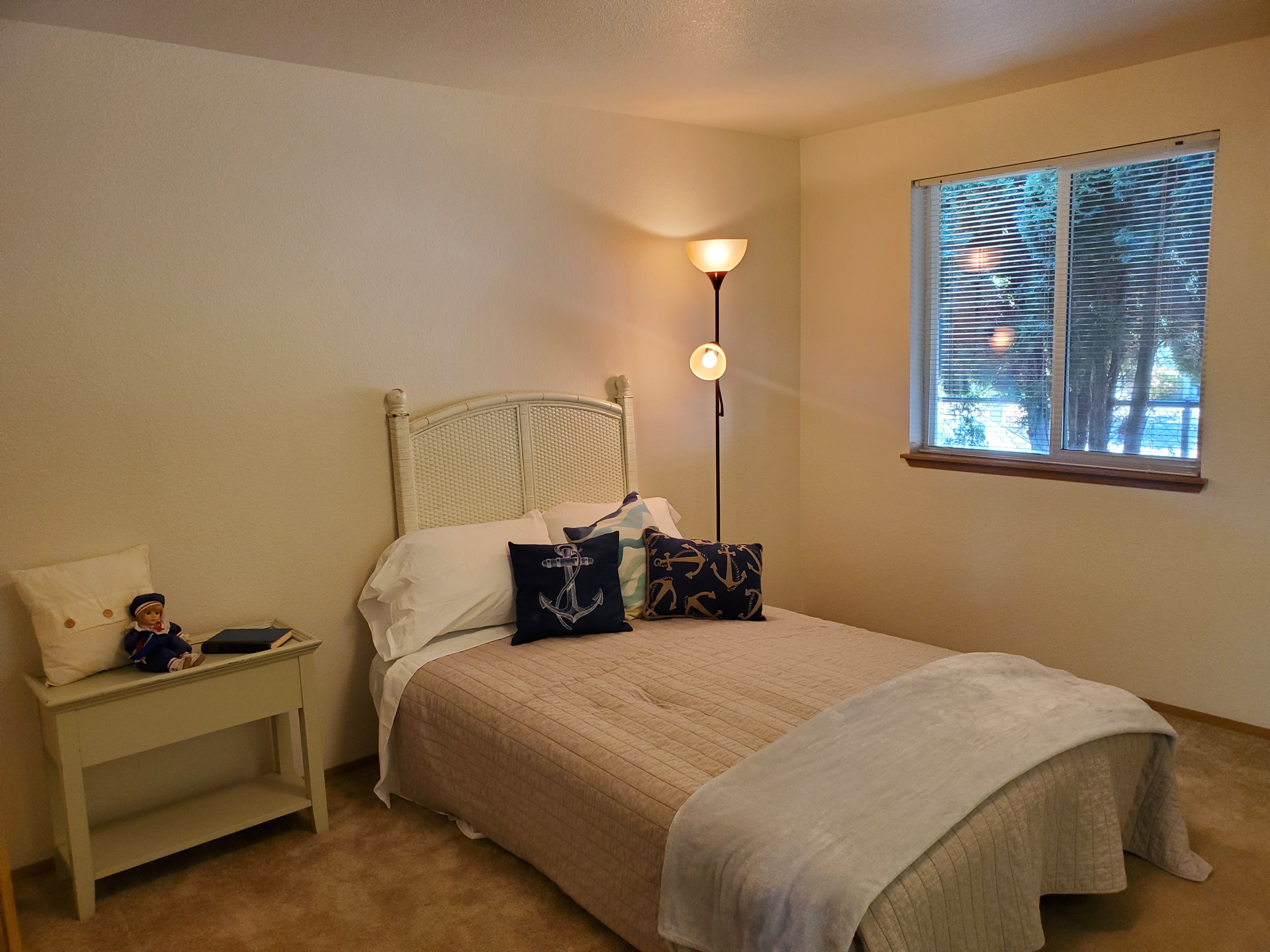 A bedroom with a bed, nightstand, and a window with blinds.