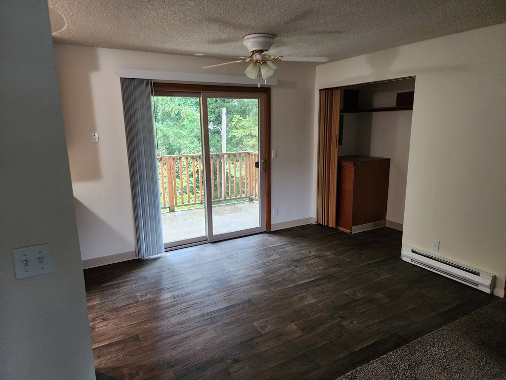 an empty living room with a sliding glass door to a balcony
