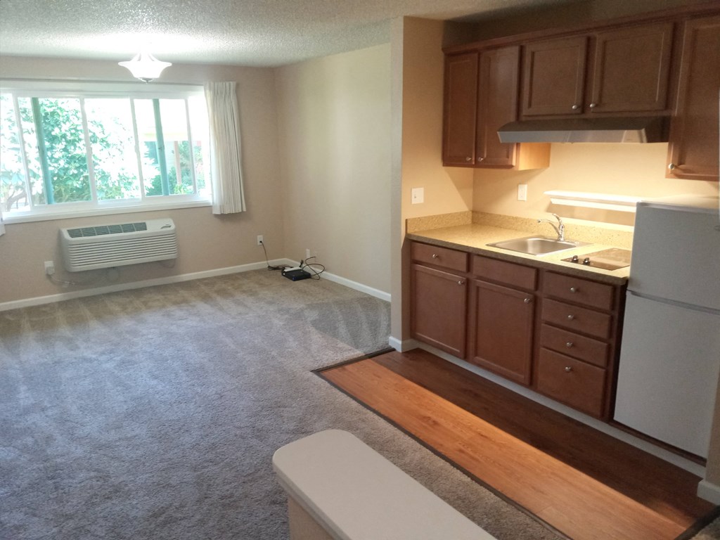 an empty kitchen with a window and a sink and a refrigerator