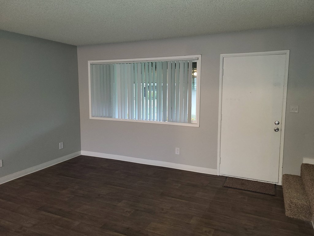 an empty living room with a window and a door