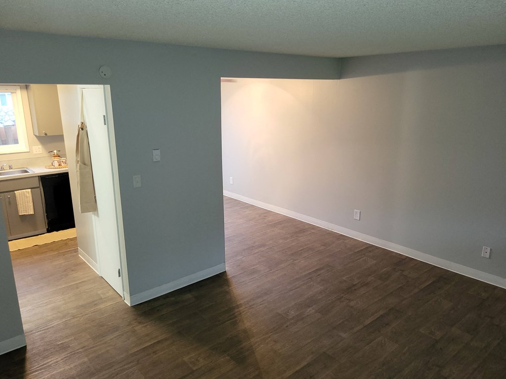 an empty living room with a hard wood floor and a white door