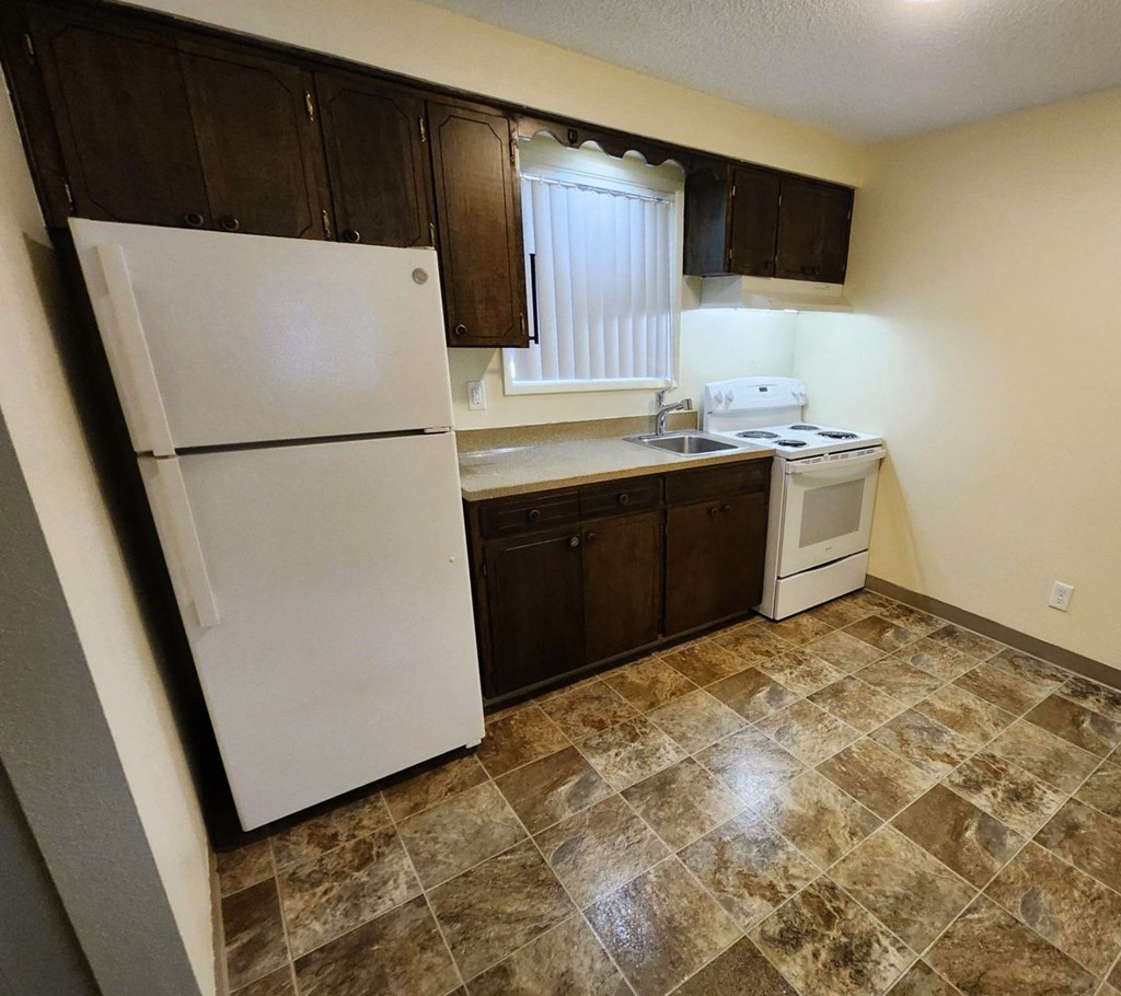 Nell Anna Court kitchen with brown cabinets and a white refrigerator.