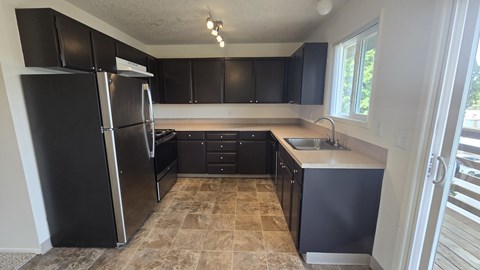 A kitchen with black cabinets and a tiled floor.