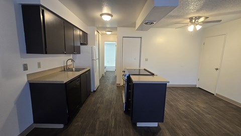 A kitchen with black cabinets and a white refrigerator.