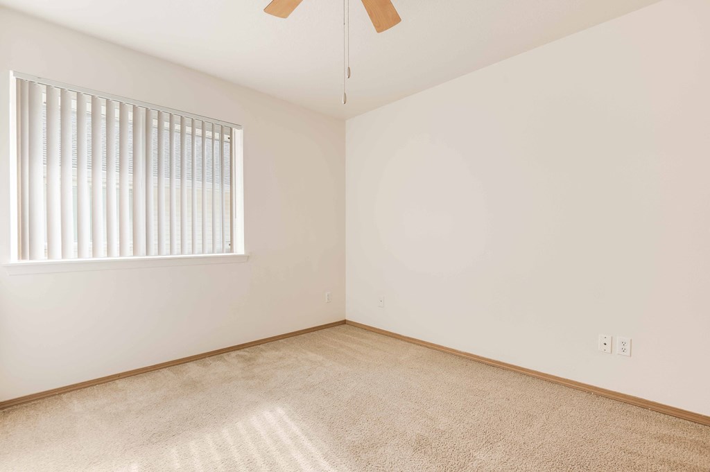 a bedroom with white walls and a window