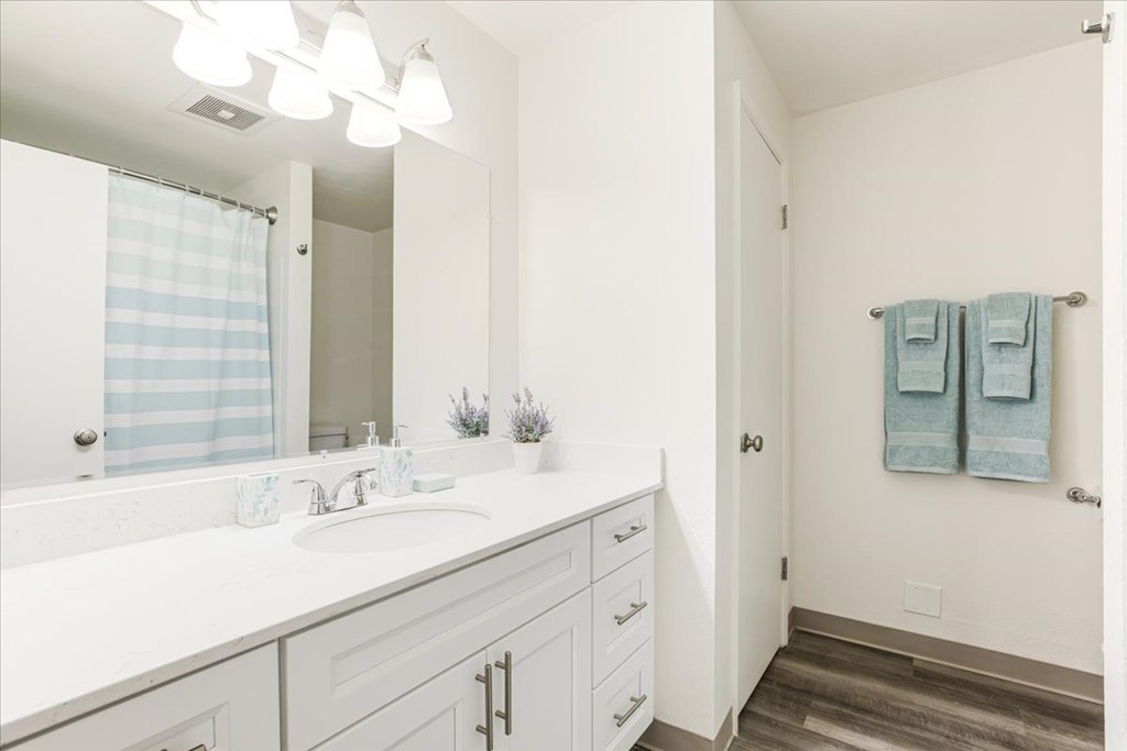 A bathroom with a white sink and a mirror above it.