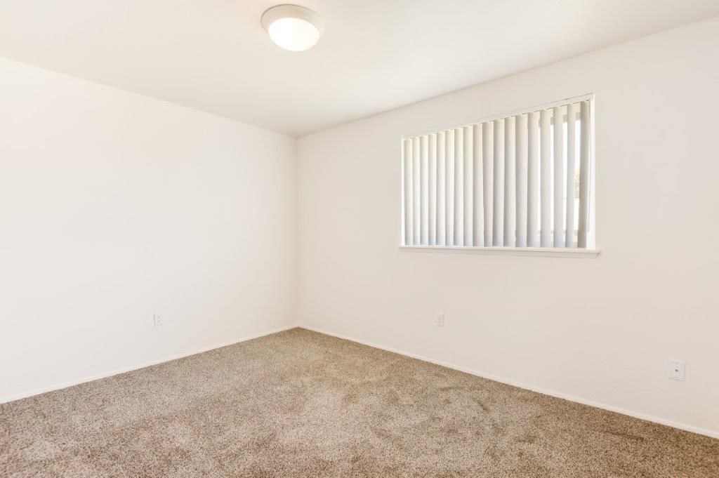 a bedroom with white walls and a window