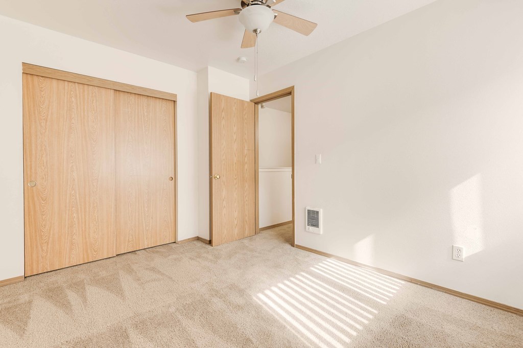 a bedroom with white walls and a ceiling fan