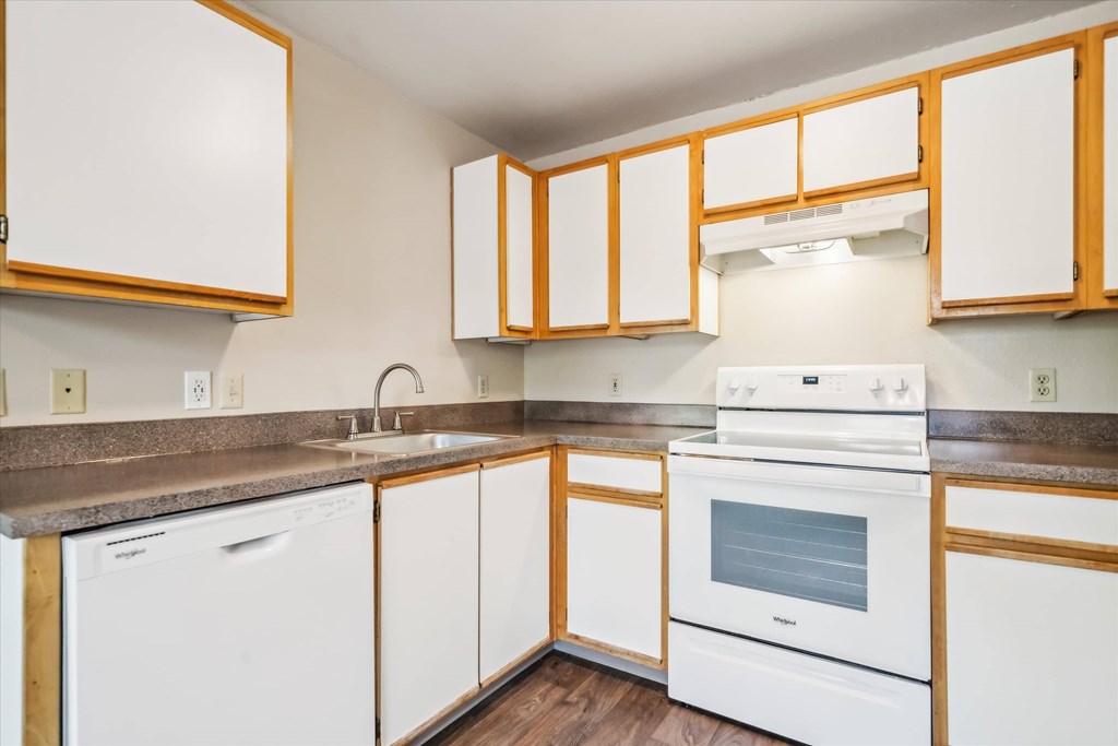 A kitchen with white appliances and wooden cabinets.