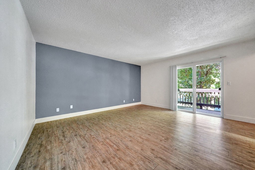a living room with hardwood floors and a sliding glass door to a balcony