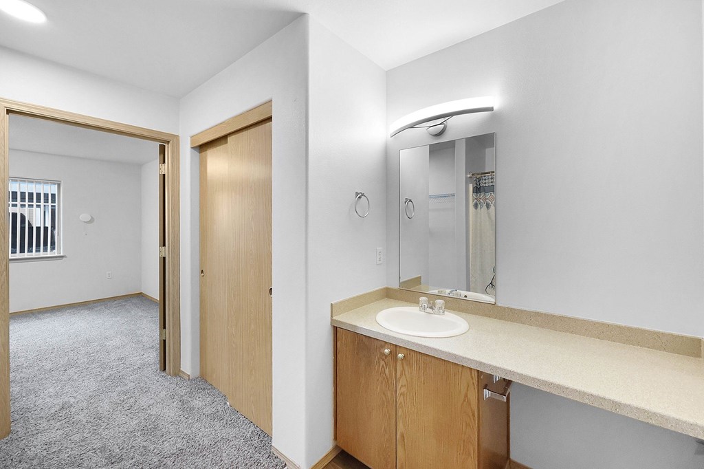 A bathroom with a sink, mirror, and a door.