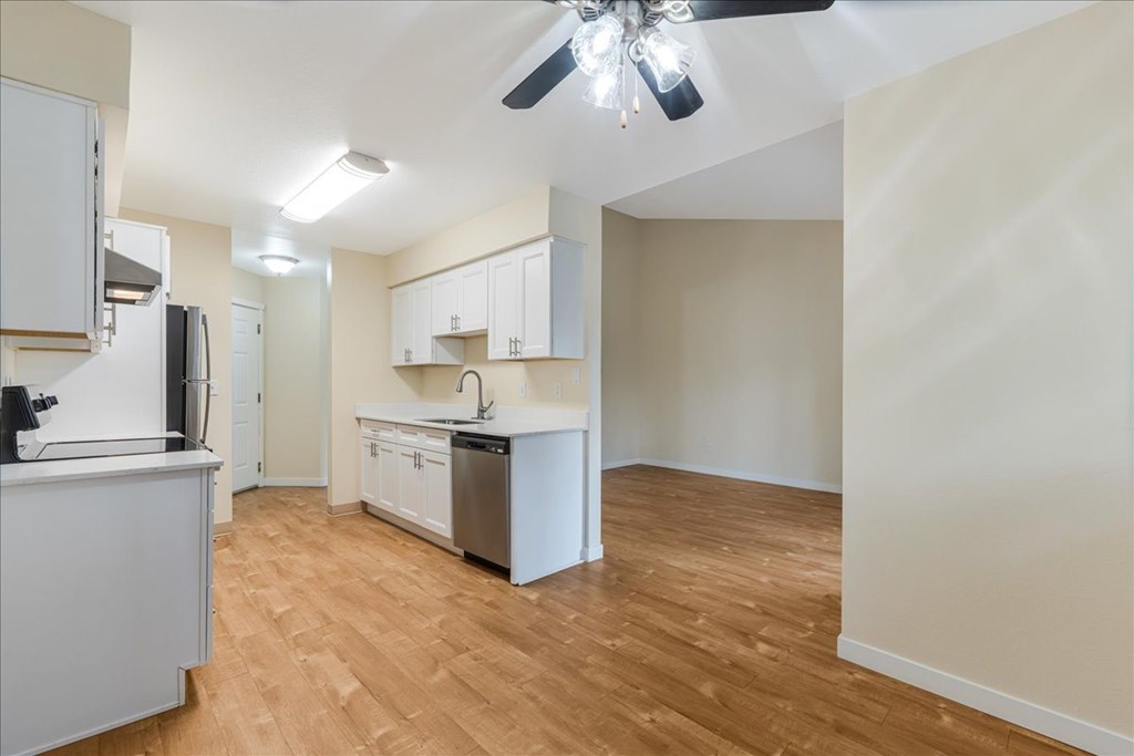A kitchen with white cabinets and a wooden floor.