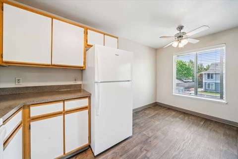 A white refrigerator in a kitchen with wooden cabinets.