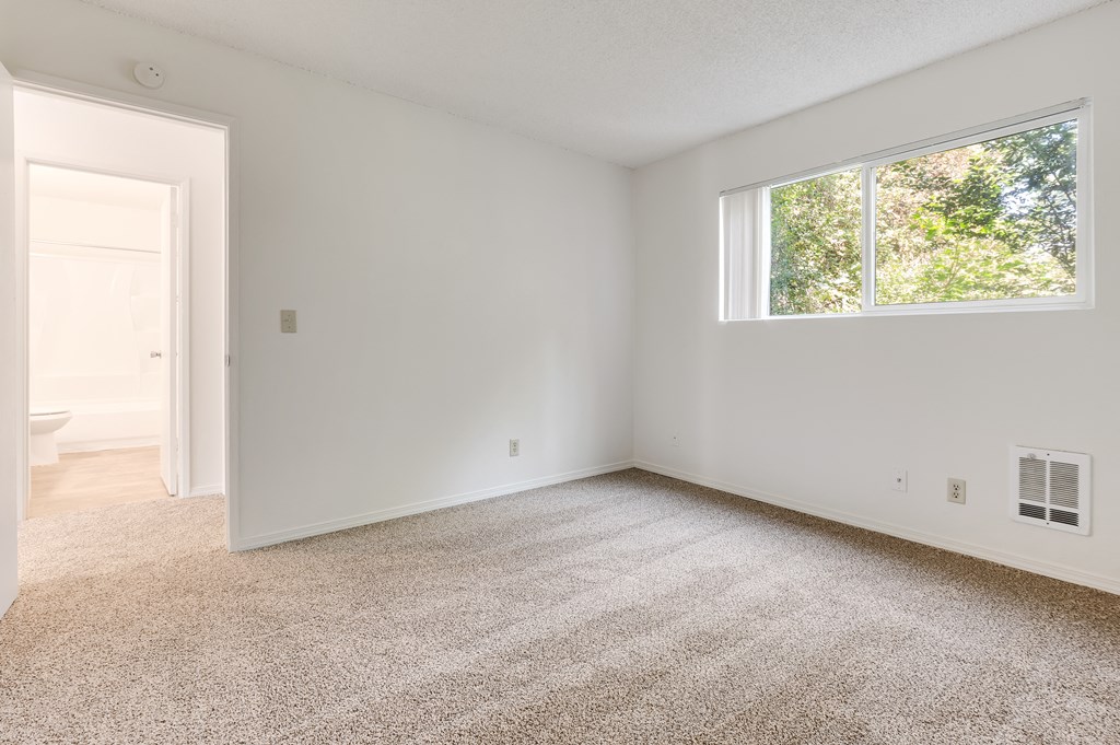 an empty room with a window and a door to a bathroom