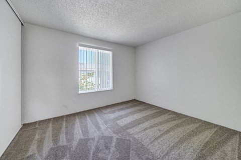 a bedroom with a window and a carpeted floor