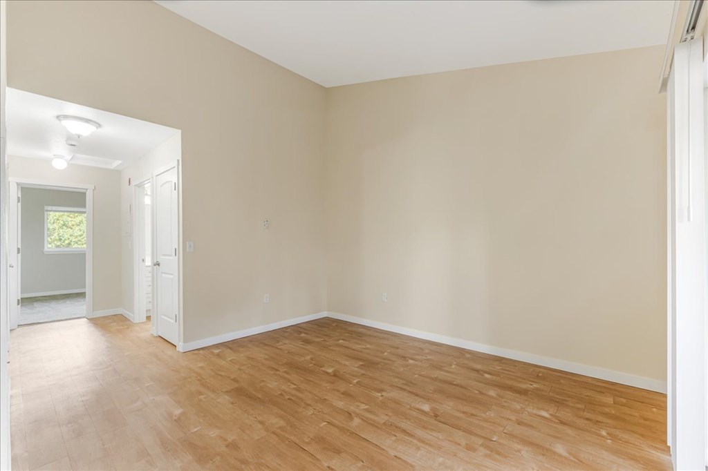 Empty room with wooden flooring and white walls.
