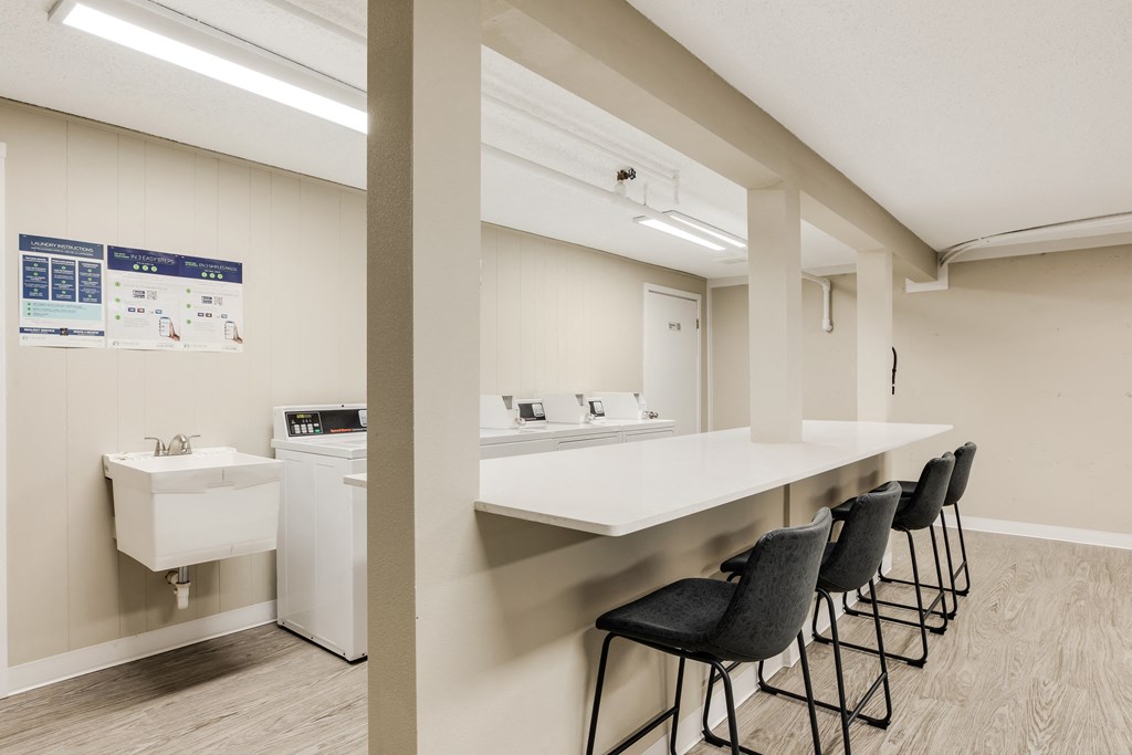 a kitchen with a counter and chairs and a sink