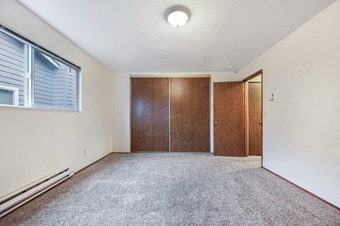 an empty living room with a closet and a window