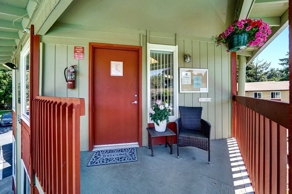 a front porch with a red door and two chairs