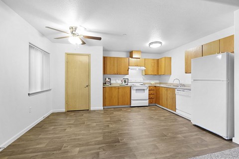 A kitchen with wooden floors and white appliances.